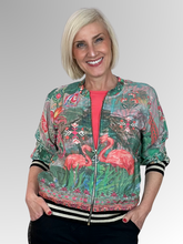 Bring playful style to your wardrobe with Orientique’s Flamingo Digital Print Zip Jacket. Crafted from lightweight rayon with a luxurious satin finish, it offers effortless comfort in a relaxed bomber silhouette. The striking digital print is perfectly elevated by eye-catching black and gold lurex bands at the cuffs and hem. Complete with a breezy zip front, it is the perfect fashion-forward layer to easily elevate any everyday outfit.