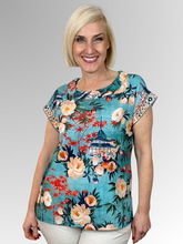 Bringing a touch of global inspiration to your everyday wardrobe, the Gordes Roll Neck Top by Orientique is an artful and effortlessly relaxed piece beautifully crafted from 100% organic cotton to ensure premium breathability and all-day comfort. This striking top features a vibrant teal base adorned with a rich print of intricate Eastern botanical and architectural motifs, perfectly balanced by a soft rolled neckline that adds a subtle, elegant detail to the upper silhouette.