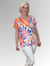 Inject a vibrant energy into your seasonal style with the Julia V-Neck Top by Escape. This stunning pullover top displays an artistic tropical design exploding with punchy shades of orange, magenta, and royal blue against a fresh cream background, balanced by an ornamental printed trim along the cuffs. Cut from premium, silky-soft rayon, it drops over the silhouette with a fluid, lightweight motion that guarantees maximum airflow and comfort during warmer months.