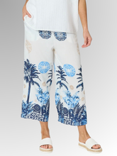 Embrace effortless summer style with the Azure Escape Print Pant, a striking statement piece designed for relaxed, warm-weather dressing. Showcasing a beautiful, resort-inspired print featuring classic palm motifs and ornate blue patterns against a crisp white background, these wide-leg pants inject modern colour and fluid movement into your everyday wardrobe. Crafted from a premium blend of Viscose and Nylon, the subtly textured fabric provides an airy, lightweight feel that is perfect for balmy climates.