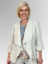 The Natural Peplum Jacket by Maglia is your perfect summer companion. Made from breathable linen, it features a stylish waterfall collar and a layered peplum for shape. With charming raw edging and fold-back 3/4-length sleeves, this versatile piece transitions effortlessly from workdays to weekend adventures. Light, playful, and effortlessly chic!
